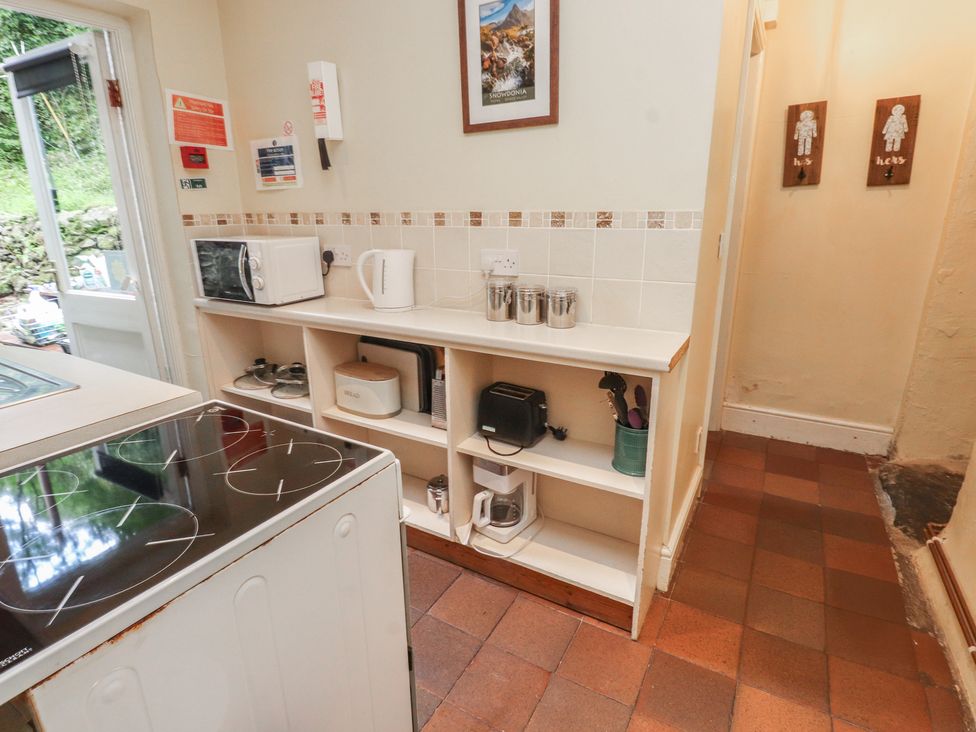 A kitchen with appliances on a shelf at Tryfan Cottage in Nant Gwynant