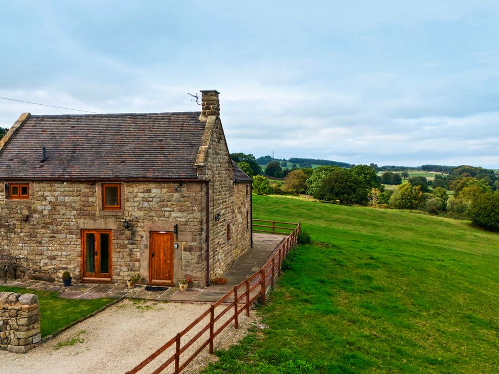 A stone cottage with wooden doors and a fence at Lane Head Cottage Alderwasley near Wirksworth