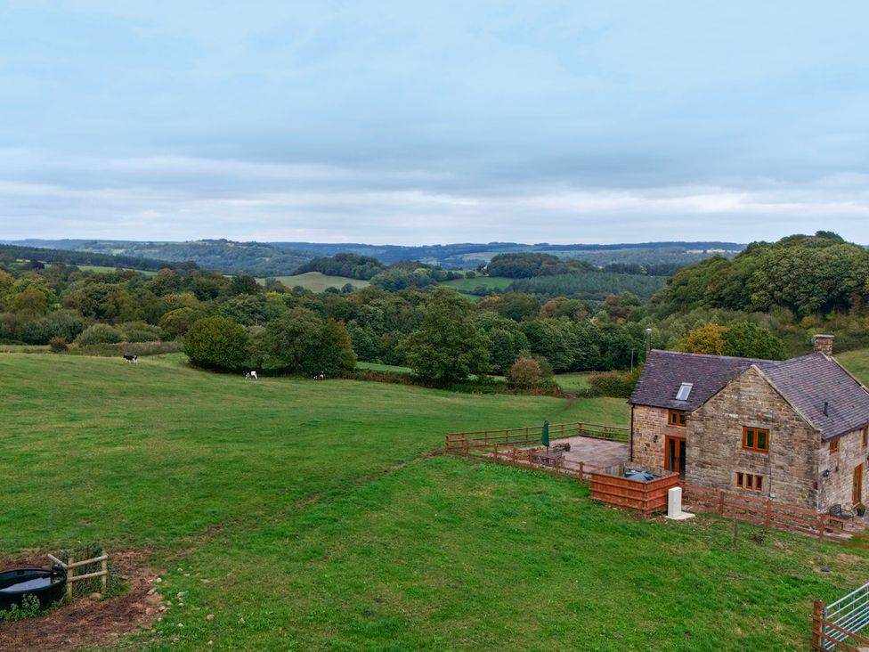 A view of a house in a field with trees and cows at Lane Head Cottage Alderwasley near Wirksworth