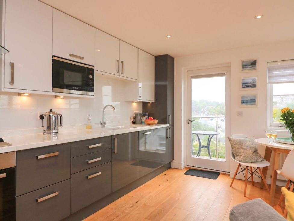 A kitchen with modern appliances and a small dining table at 61B Fore Street Kingsbridge