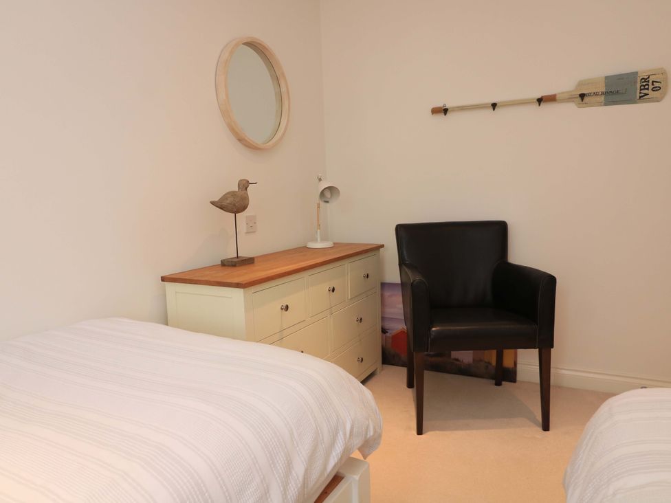 A bedroom with two beds and a chair at 61B Fore Street in Kingsbridge
