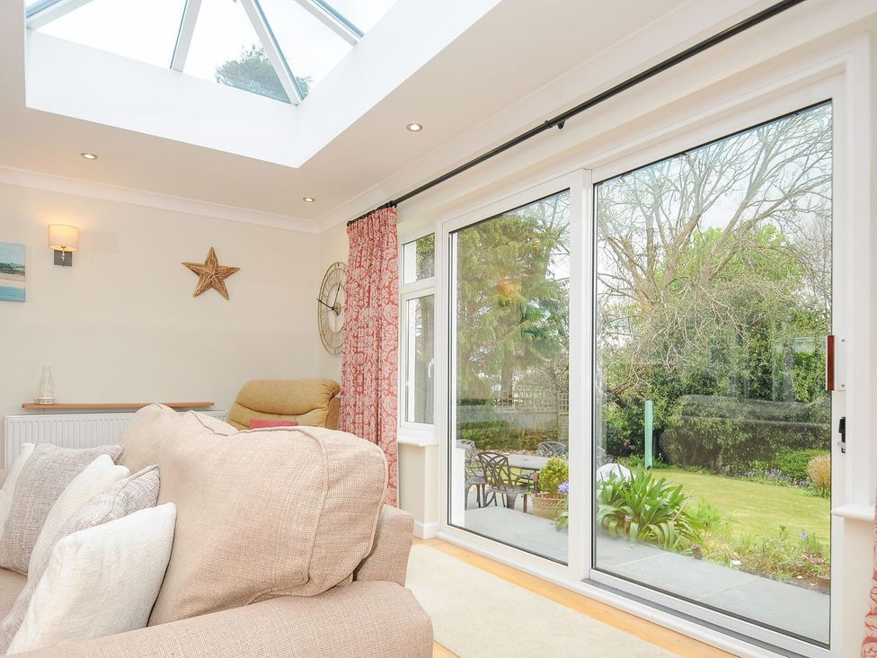 A conservatory with a sofa and window overlooking a garden at Chimings Rock