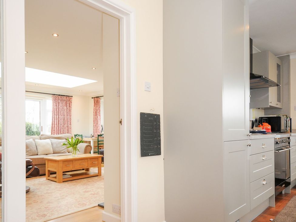 A kitchen with cabinets and an open doorway to a living room at Chimings Rock