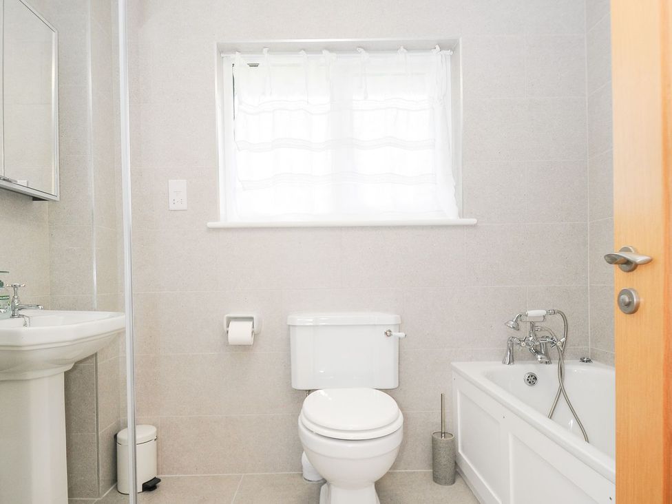 A bathroom with a toilet, sink, mirror, and bathtub at Chimings in Rock