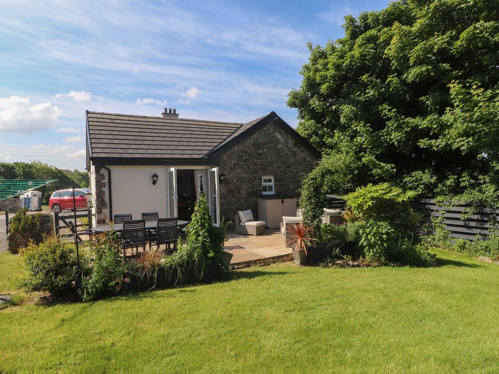 A garden with a patio and outdoor furniture next to a small house at Annexe at Ty Moel Isaf in Pengorffwysfa near Amlwch