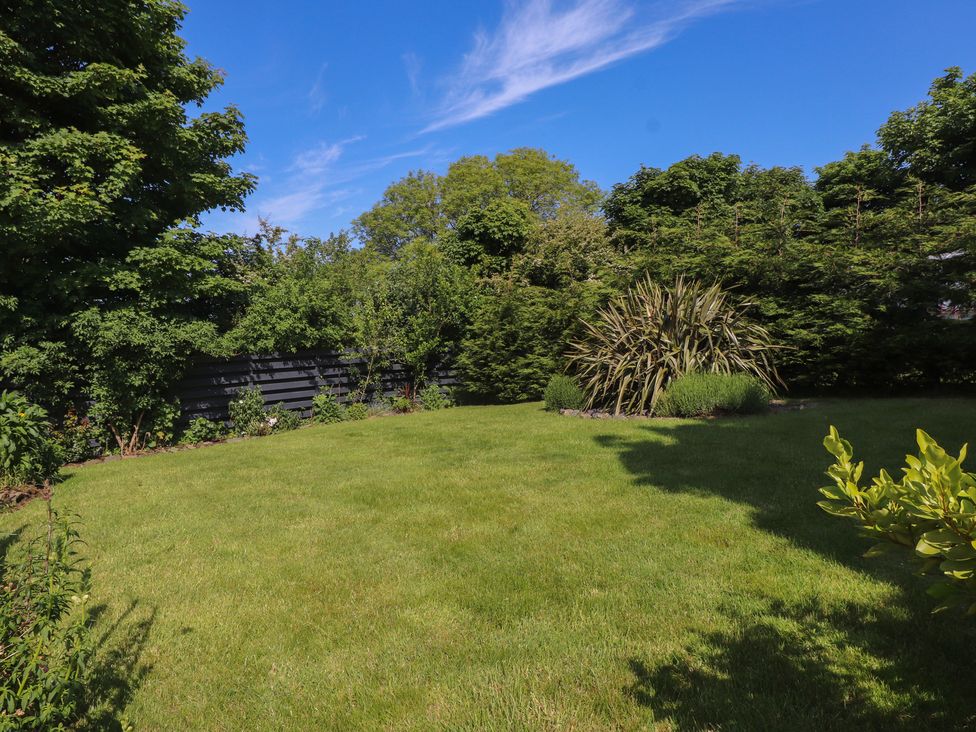 A garden with grass lawn trees and shrubs at Annexe at Ty Moel Isaf in Pengorffwysfa near Amlwch