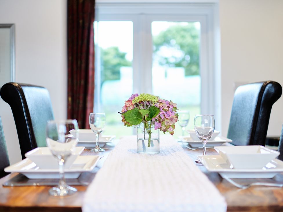 A dining table set with plates bowls glasses and a flower centerpiece at Annexe at Ty Moel Isaf in Pengorffwysfa near Amlwch
