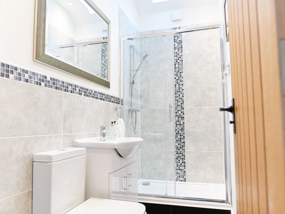 A bathroom with a toilet sink mirror and a glass shower enclosure at Annexe at Ty Moel Isaf in Pengorffwysfa near Amlwch