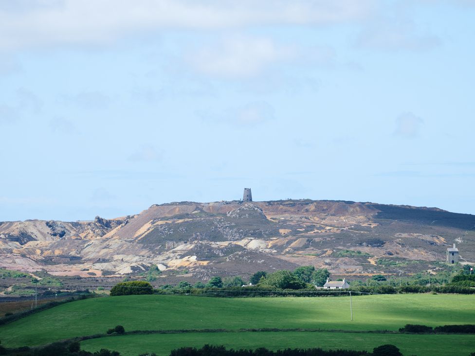 A landscape view with green fields in the foreground and hills with stone towers in the background at Annexe at Ty Moel Isaf in Pengorffwysfa near Amlwch
