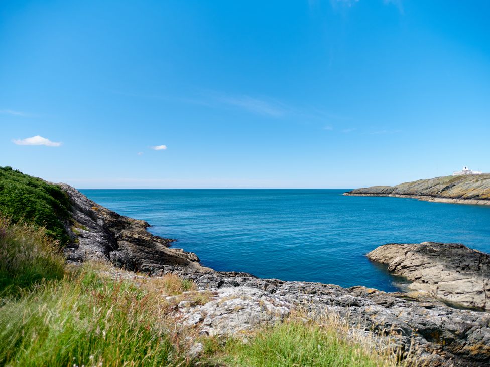 A coastal landscape with rocky cliffs and blue sea under a clear sky at Annexe at Ty Moel Isaf in Pengorffwysfa near Amlwch