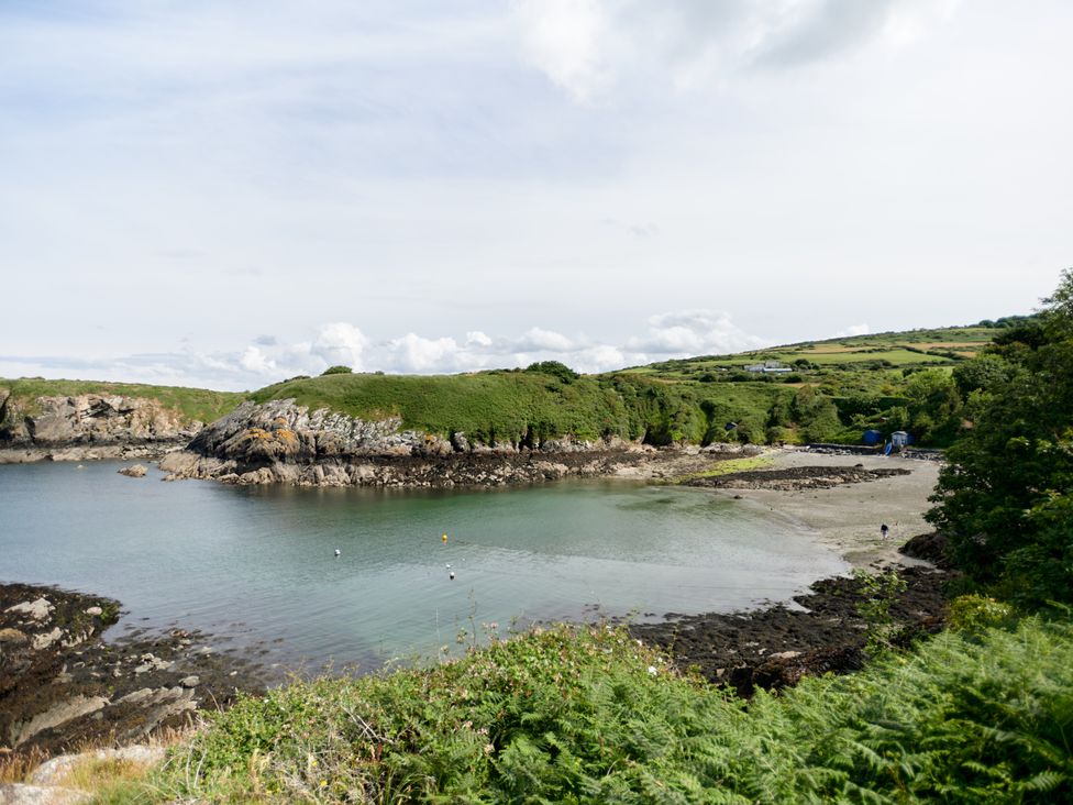 A coastal bay with rocky shoreline and green hills in the background at Annexe at Ty Moel Isaf Pengorffwysfa near Amlwch