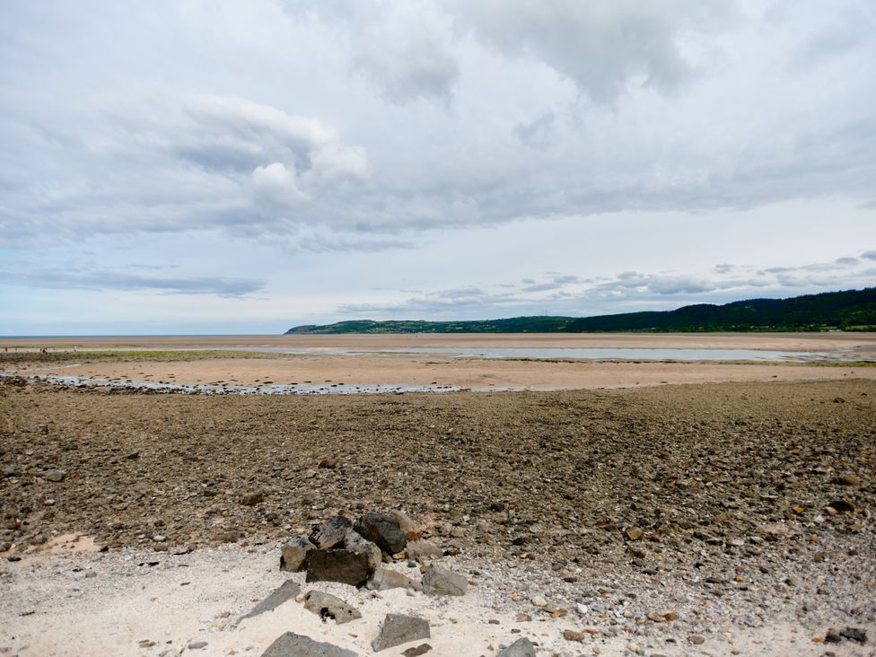 A rocky beach with sandy areas and hills in the distance at Annexe at Ty Moel Isaf Pengorffwysfa near Amlwch