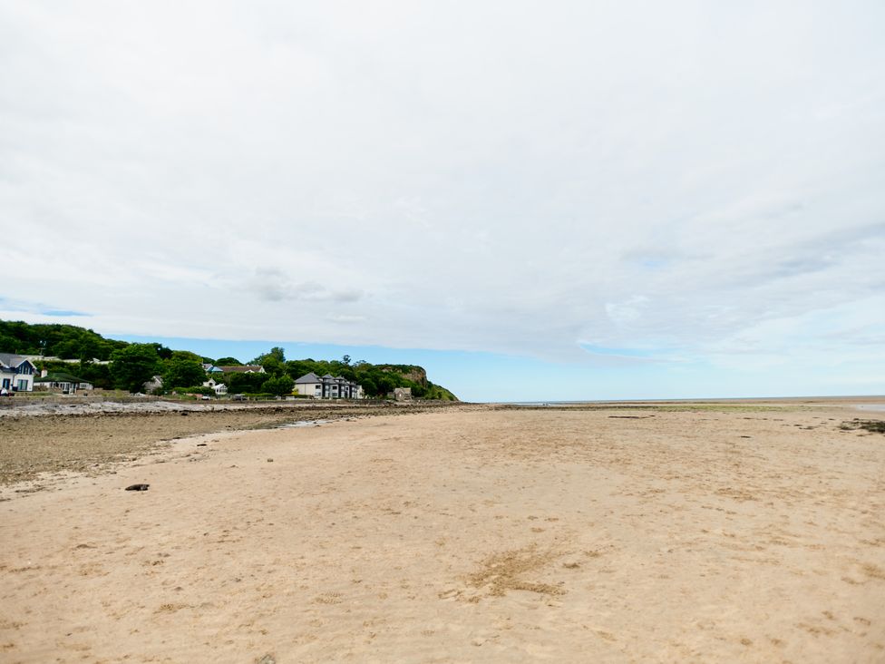 A sandy beach with scattered rocks and houses along the shoreline at Annexe at Ty Moel Isaf in Pengorffwysfa near Amlwch