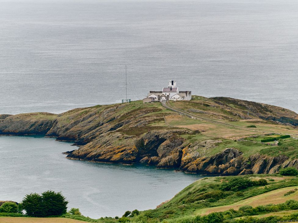 A coastal landscape with a lighthouse on a rocky headland surrounded by water at Annexe at Ty Moel Isaf in Pengorffwysfa near Amlwch