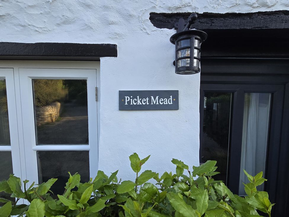 A sign for Picket Mead near a window and door outside