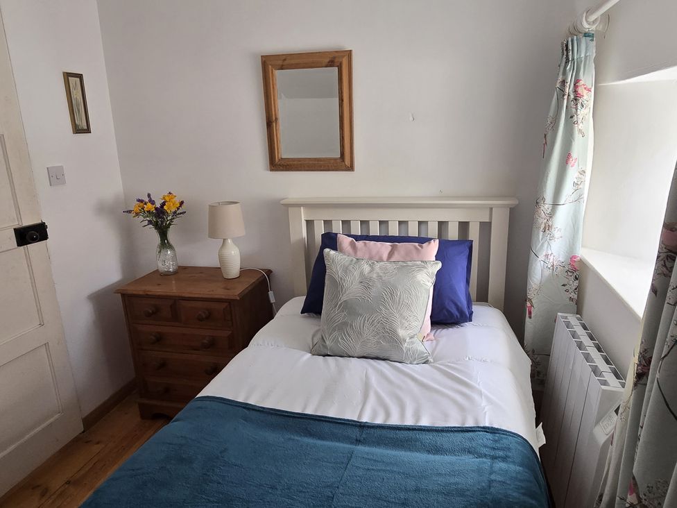A bedroom with a bed, nightstand, mirror and lamp at Picket Mead Southleigh near Colyton
