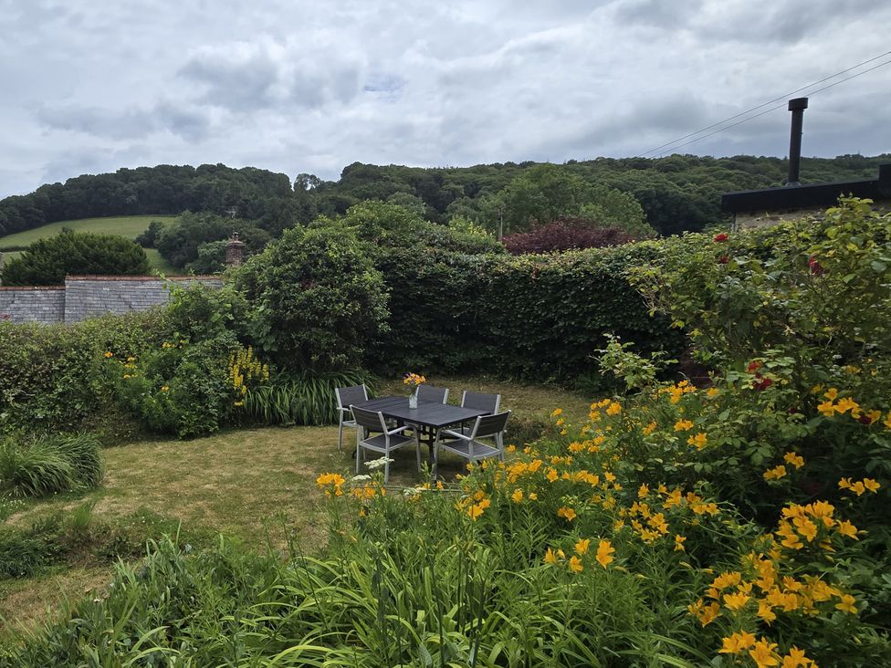 A garden with a table and chairs surrounded by flowers at Picket Mead Southleigh near Colyton
