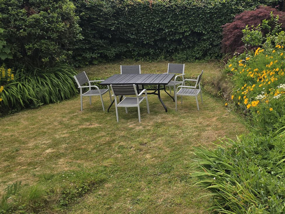 A garden with a table and chairs surrounded by plants at Picket Mead in Southleigh near Colyton