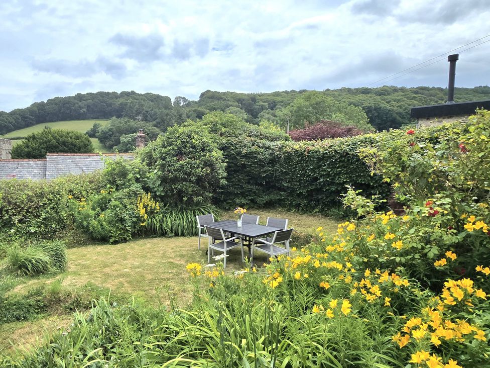 A garden with a table and chairs surrounded by flowers at Picket Mead Southleigh near Colyton