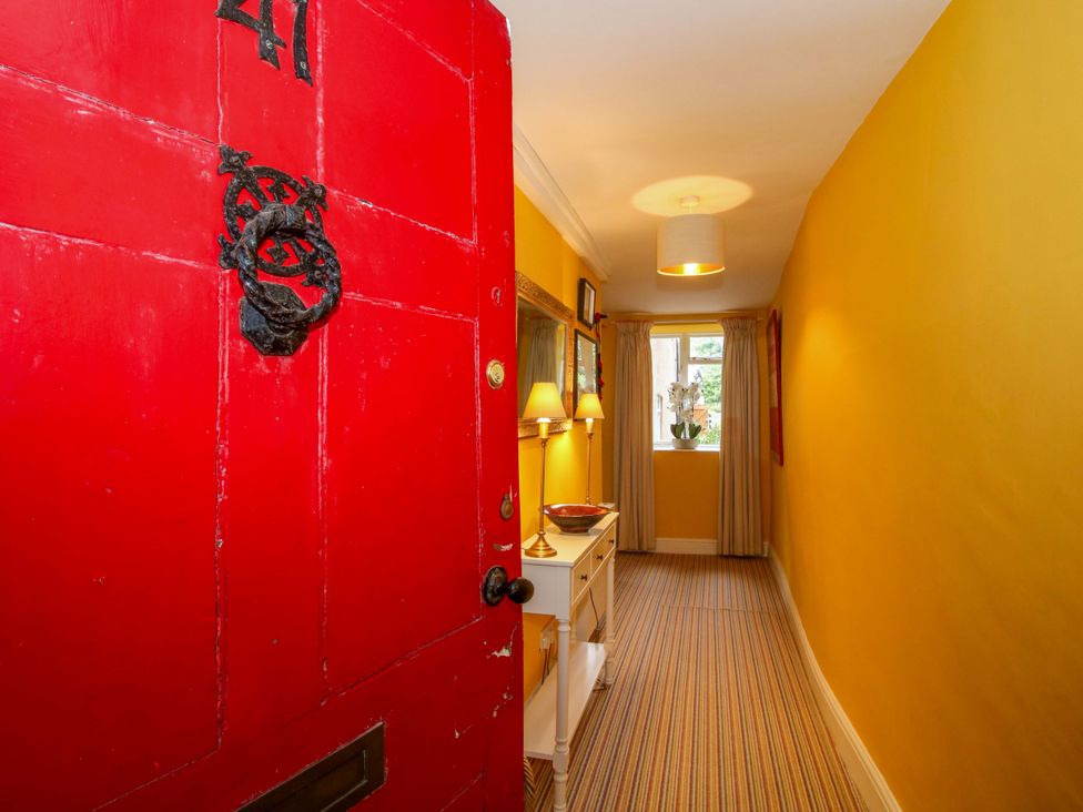 A hallway with a red door and a table at 41 High Street in Bishop's Castle