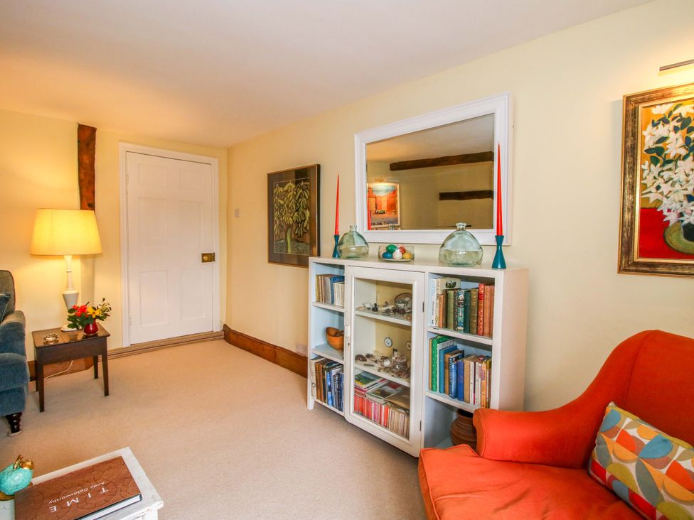 A living room with a bookcase and an orange chair at 41 High Street Bishop's Castle