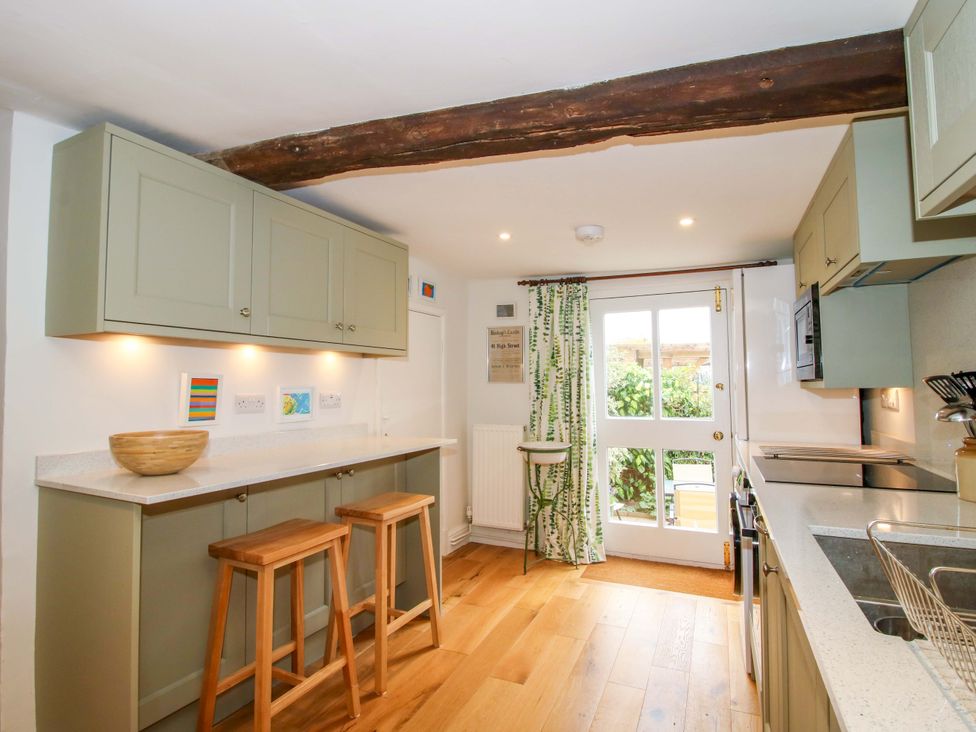 A kitchen with cabinets, counter and stools at 41 High Street in Bishop's Castle