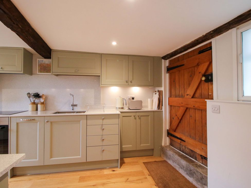 A kitchen with cabinets, sink, kettle, and wooden door at 41 High Street in Bishop's Castle