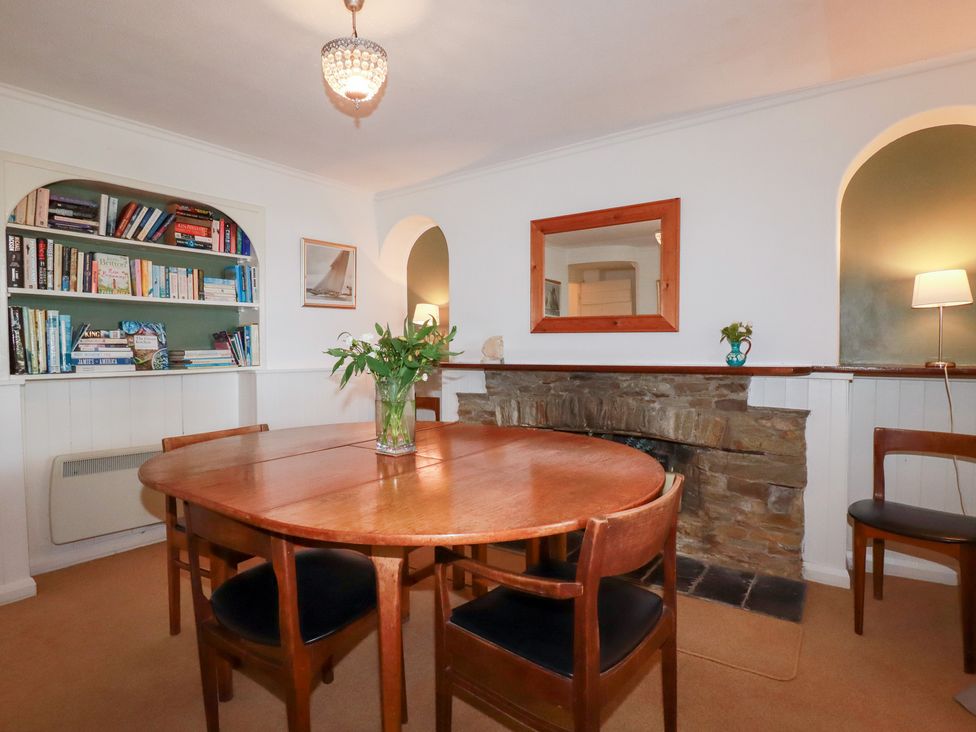 A dining room with a round table and bookshelf at Nanvivian in Feock near Truro