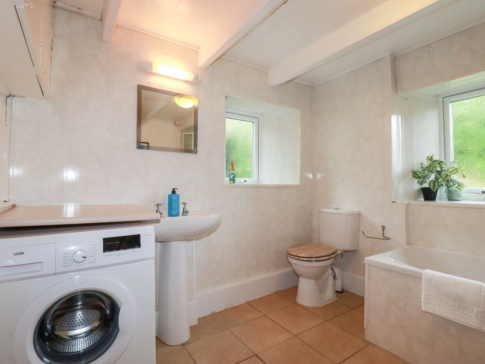 A bathroom with a washing machine, sink, and bathtub at Nanvivian in Feock near Truro