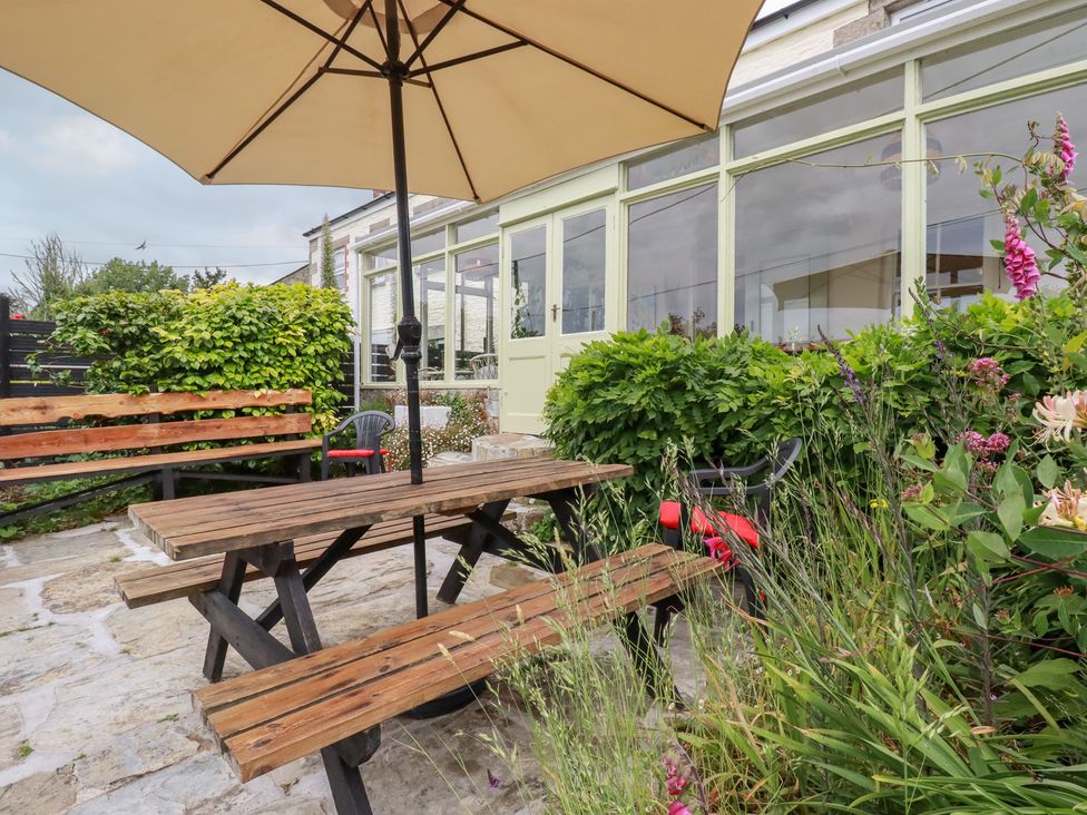 A dining table with an umbrella and benches at Nanvivian in Feock near Truro