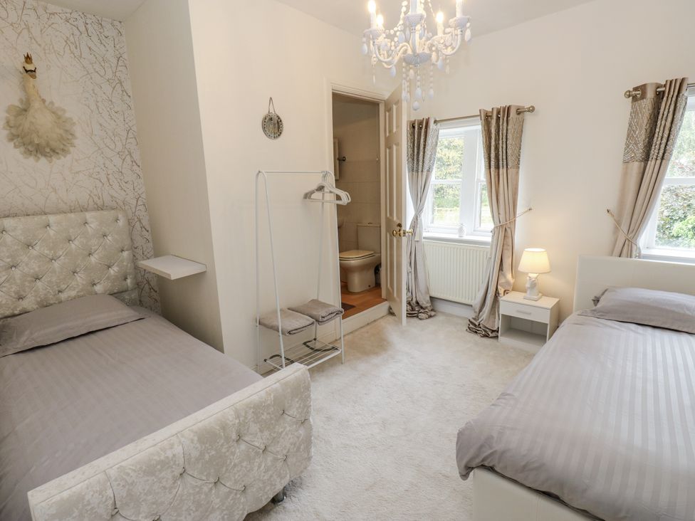 A bedroom with two beds and a bathroom entrance at Cold Spring House Cullingworth