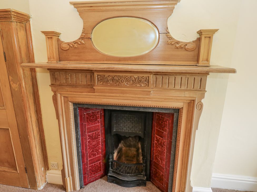 A fireplace with a mantel and decorative tiles at Cold Spring House in Cullingworth