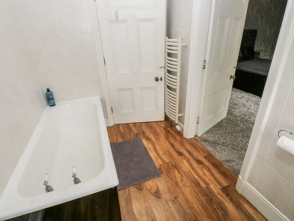 A bathroom with a bathtub and towel rail at Cold Spring House in Cullingworth