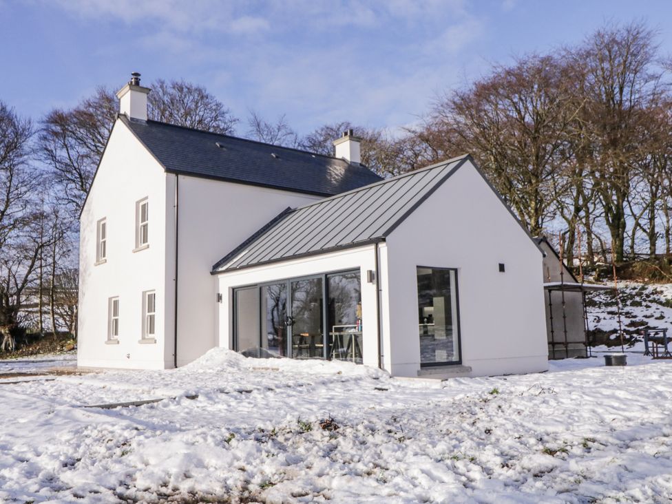 A house covered in snow with trees in the background at Cloneytrace Mines