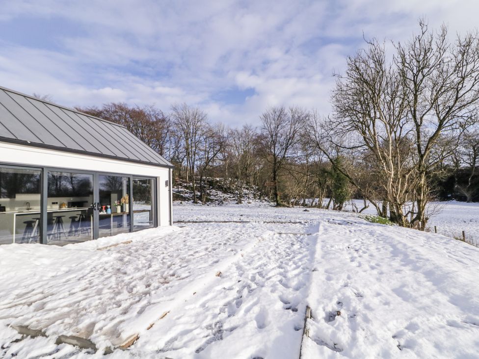 A snowy outdoor area with a house and trees at Cloneytrace Mines