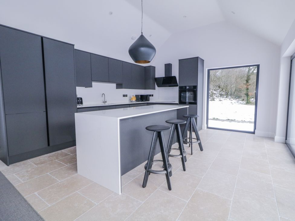 A kitchen with black cabinets and stools at Cloneytrace Mines 