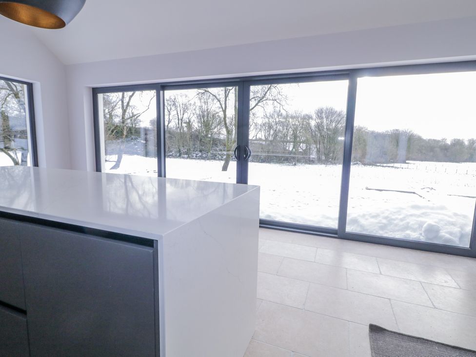 A kitchen with a large island and windows showing snow outside at Cloneytrace Mines