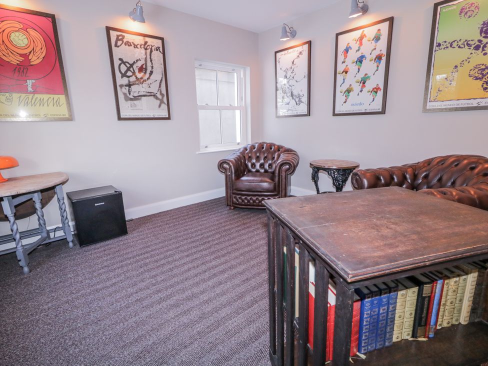 A sitting room with a leather armchair and bookshelves at Cloneytrace Mines