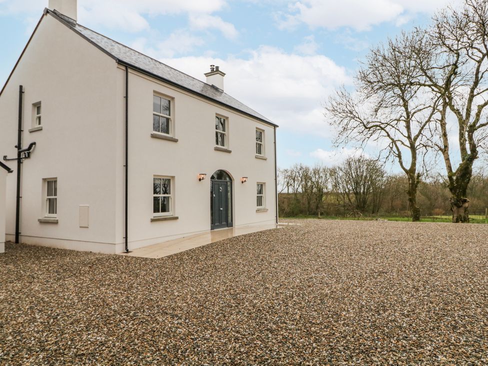 A house with a gravel driveway and trees at Cloneytrace Mines Broughshane