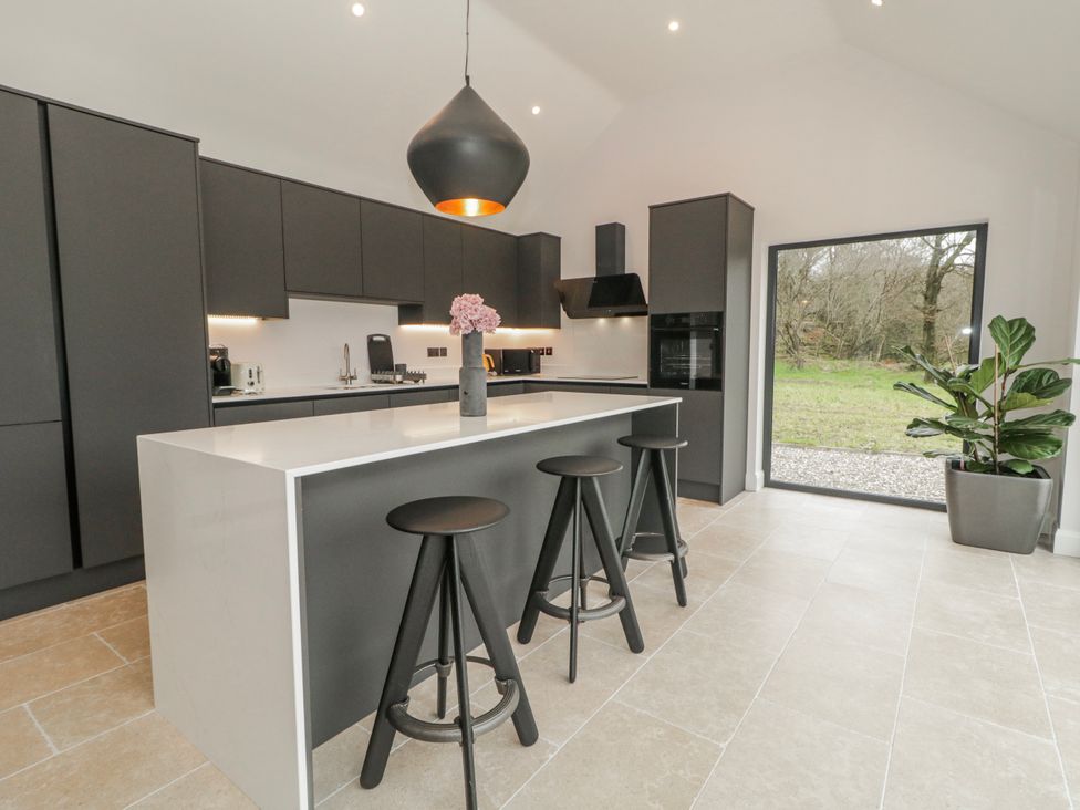 A kitchen with an island and black cabinets at Cloneytrace Mines in Broughshane