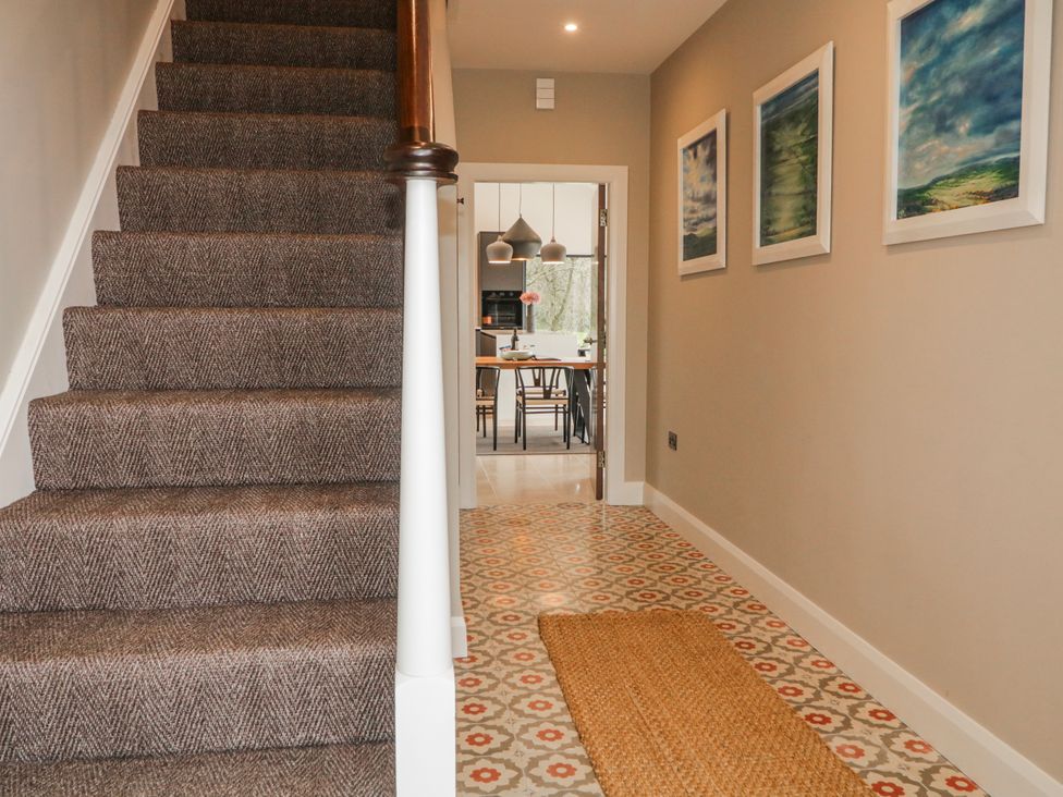 A hallway with stairs and paintings leading to a dining area at Cloneytrace Mines Broughshane