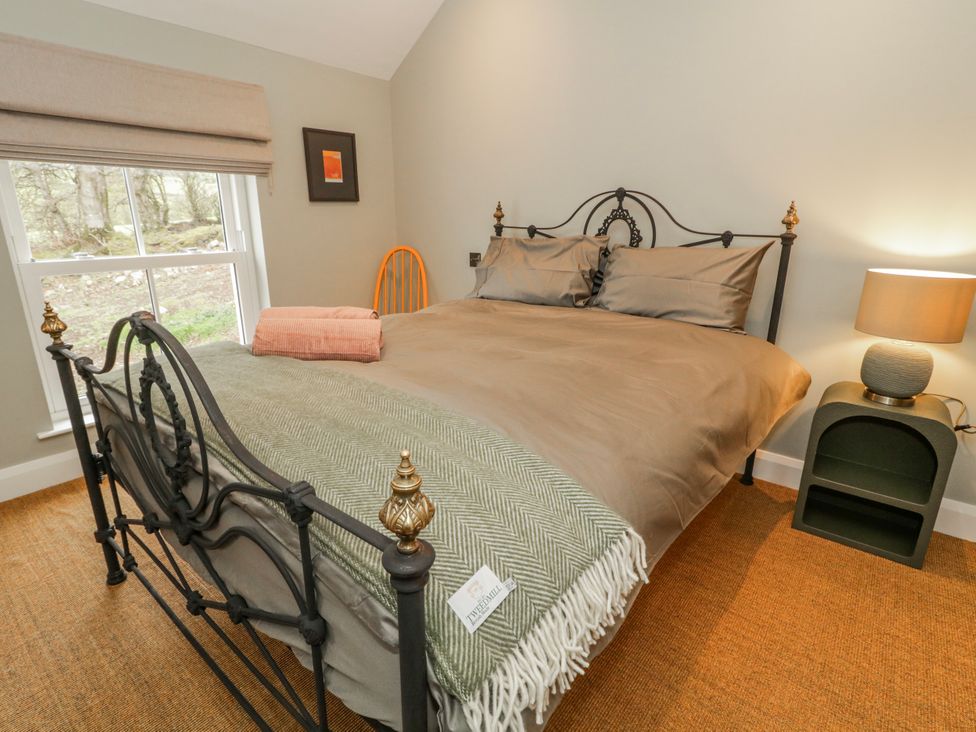A bedroom with a bed and a window overlooking trees at Cloneytrace Mines in Broughshane