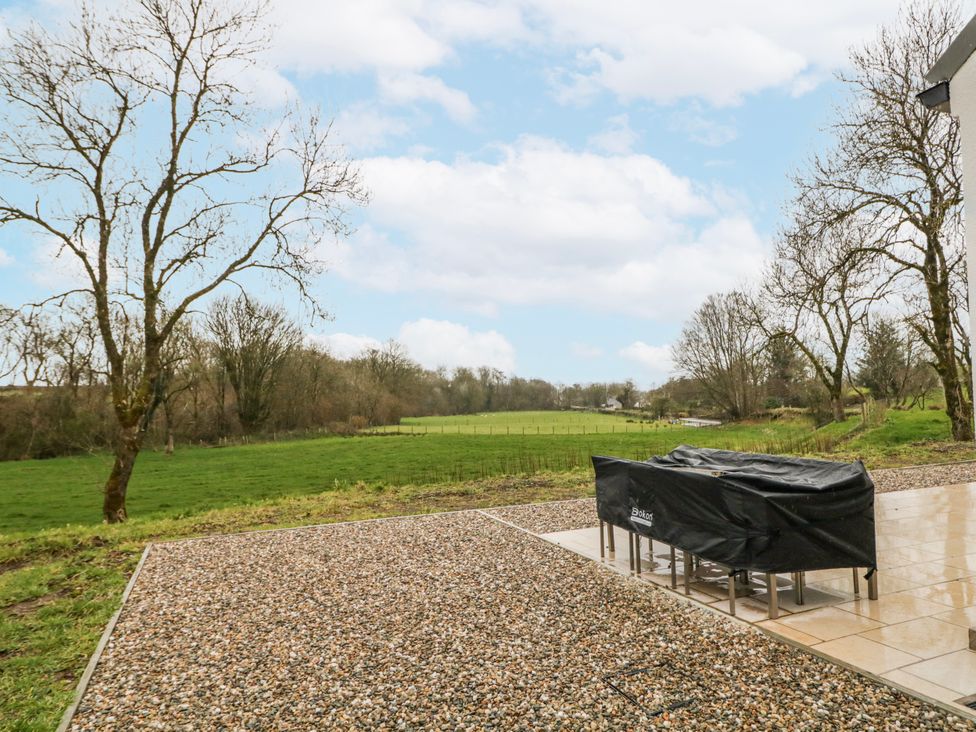 A patio area with a table cover and trees at Cloneytrace Mines in Broughshane