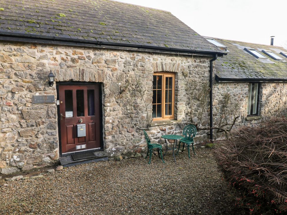An outdoor area with a stone wall and a table with chairs at Elder Cottage in Haverfordwest
