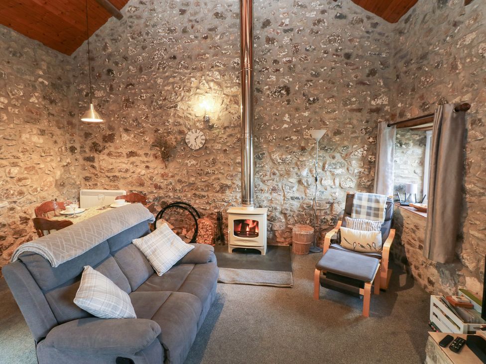 A living room with a sofa and dining area at 8 Rogeston Cottages Haverfordwest