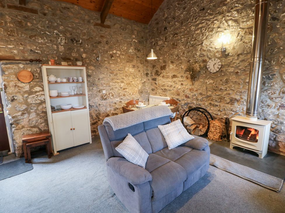 A living room with a sofa, dining table and wood stove at 8 Rogeston Cottages Haverfordwest