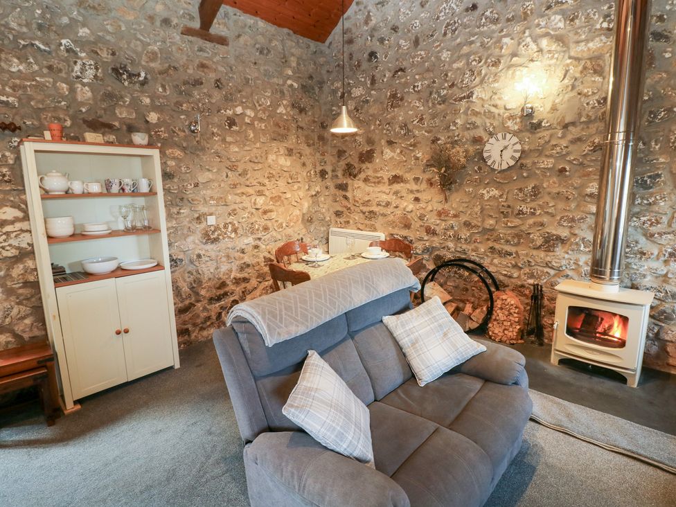 A living room with a sofa and dining area at 8 Rogeston Cottages Haverfordwest