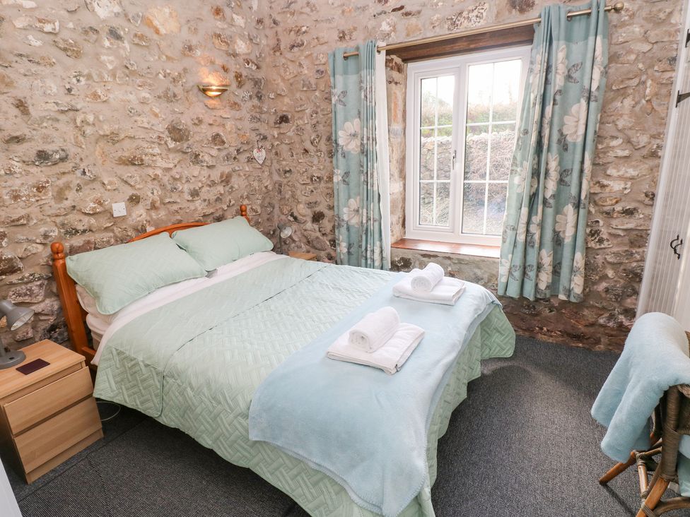 A bedroom with a bed and window at 8 Rogeston Cottages in Haverfordwest