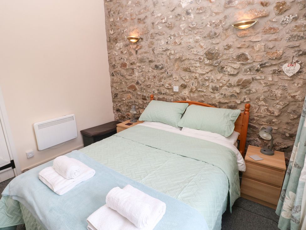 A bedroom with a double bed and stone wall at 8 Rogeston Cottages Haverfordwest