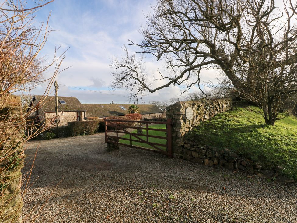 A gate leading to a gravel driveway with buildings and trees at 8 Rogeston Cottages Haverfordwest